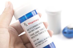 Victim holding blue pill bottle hires metformin lawsuit lawyer after metformin cancer diagnosis.