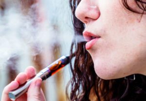Woman risking getting a vape lung injury by smoke e-cigarette.
