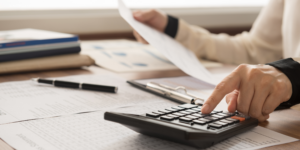 persona sacando cuentas con calculadora y talonario del trabajo