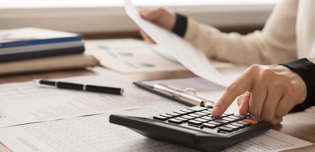 persona sacando cuentas con calculadora y talonario del trabajo