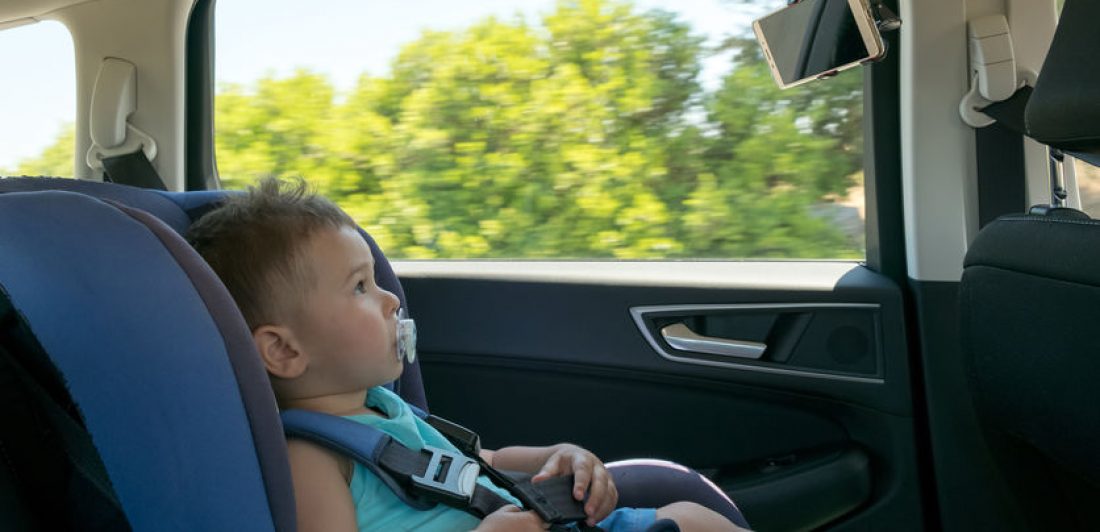 Baby boy in a car on child safety seat watching cartoon on the tablet registrar el asiento de seguridad