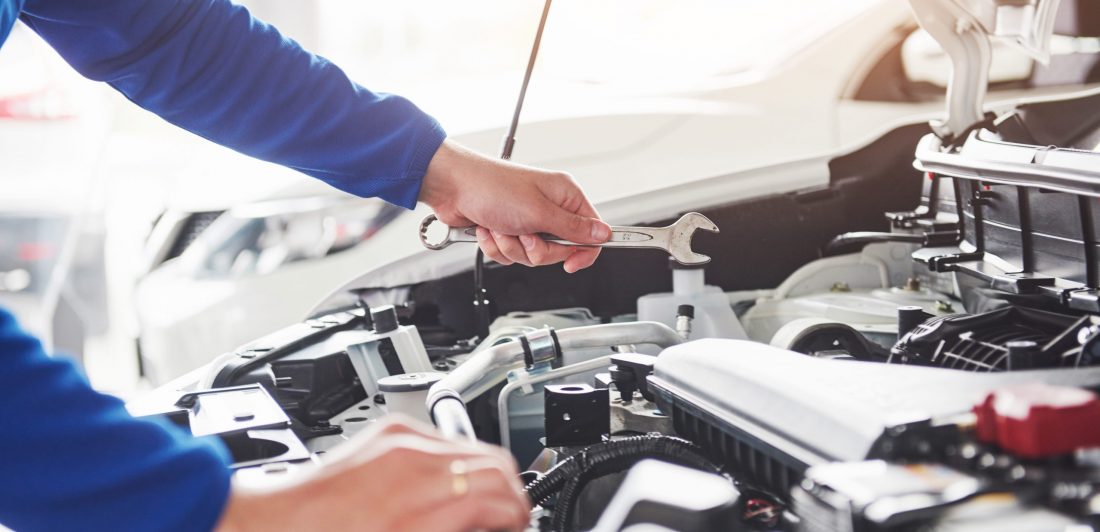 Hands of car mechanic with wrench in garage