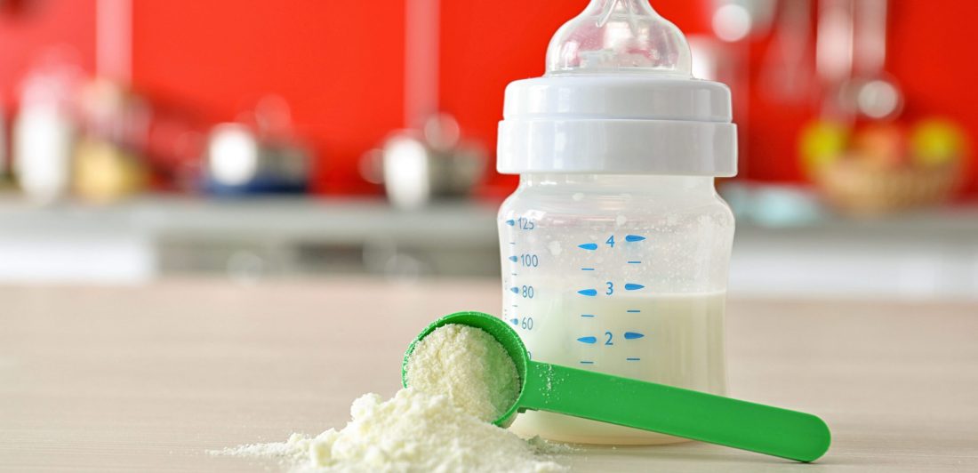 Feeding bottle and baby milk formula on kitchen background