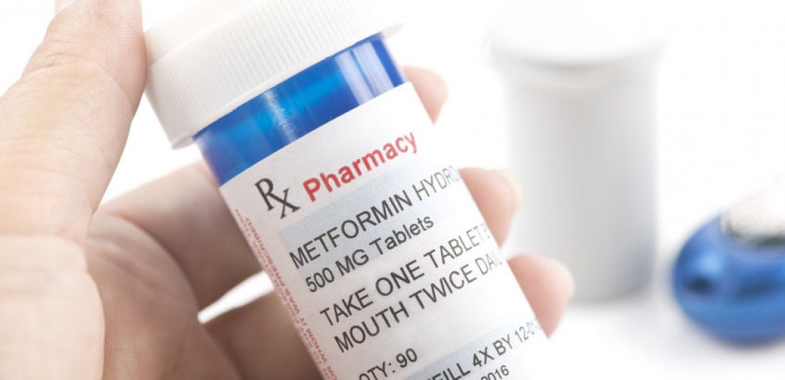 Metformin pill bottle Victim holding blue pill bottle hires metformin lawsuit lawyer after metformin cancer diagnosis.