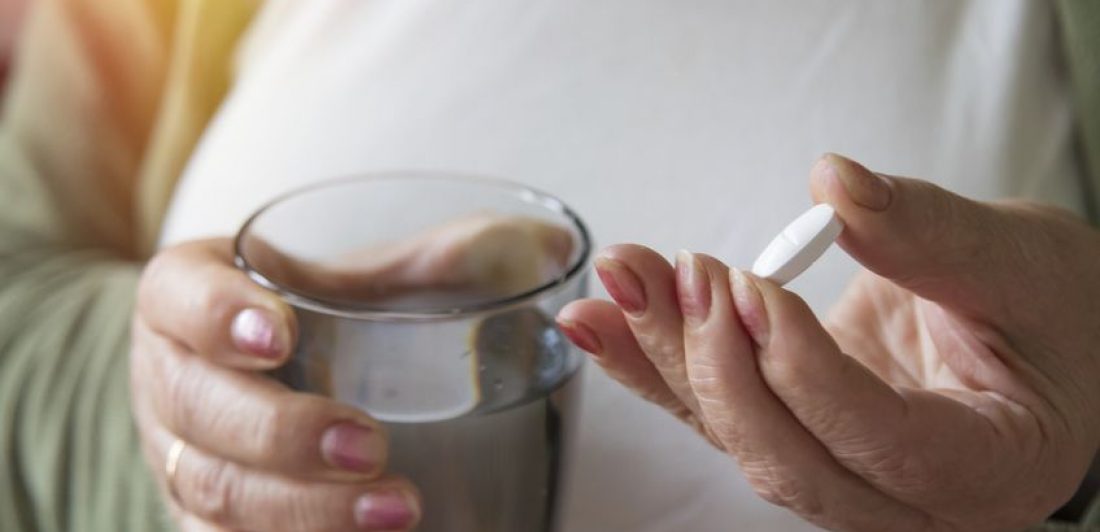 senior hand with pills and glass of water Zantac y cáncer